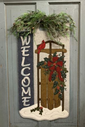 Wool applique door hanger featuring an old-fashioned sled